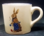 Preview: Keramik-Tasse - Becher mit Wunschname – Motiv: 2 x Osterhase mit blauer Schürze